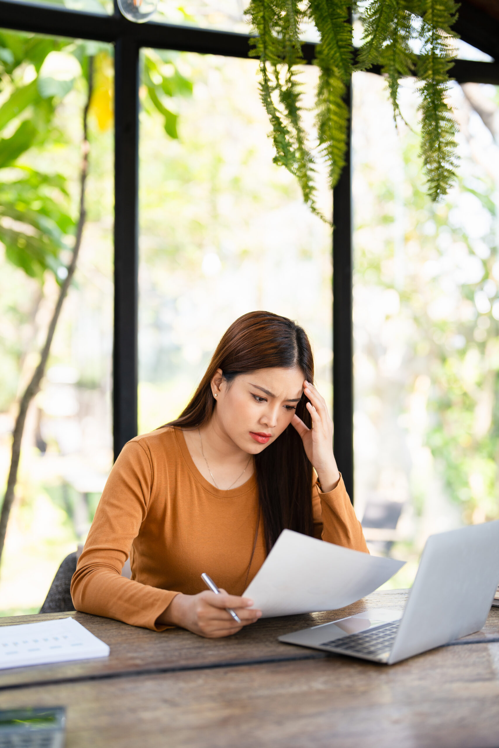 Focused young asian woman looking through paper documents, managing business affairs, summarizing taxes, planning future investments, accounting alone at home office.